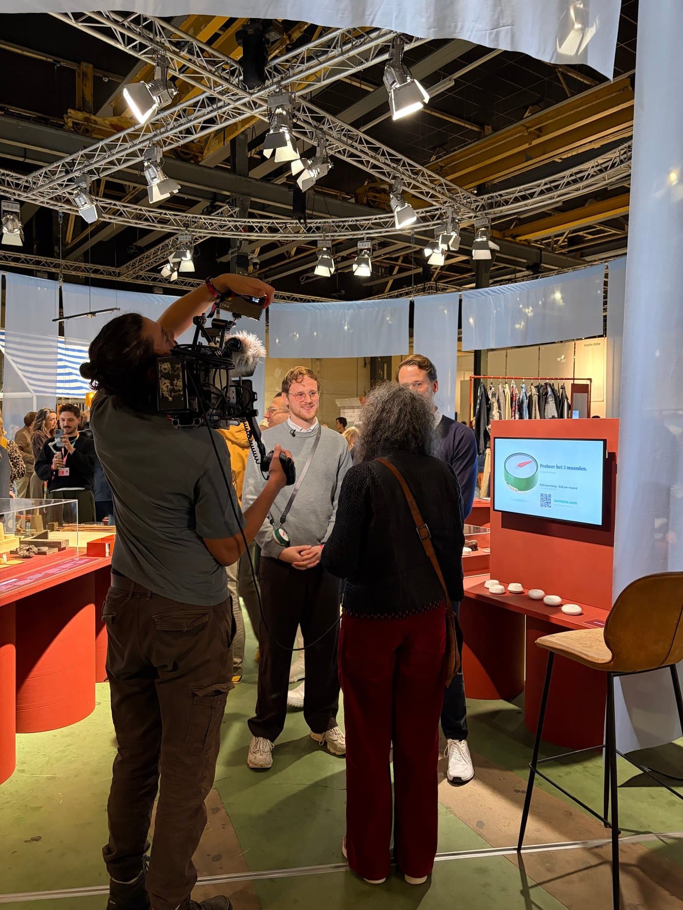 Vincent en Rick Eurlings worden geïnterviewd bij de stand van Aumens, met Het Kompas op tafel