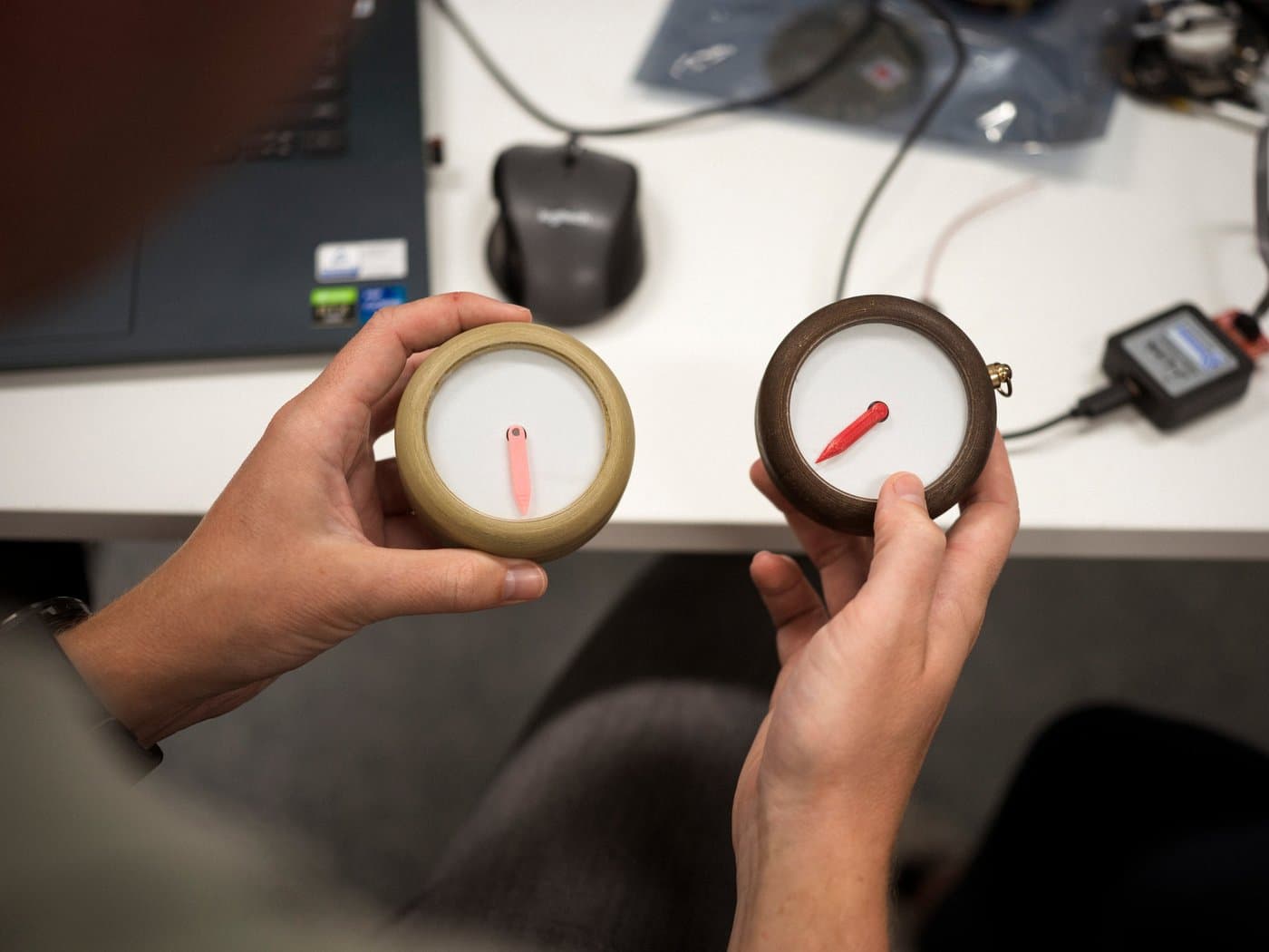 Twee vroege prototypes van Het Kompas in de handen van een ontwikkelaar, naast een laptop